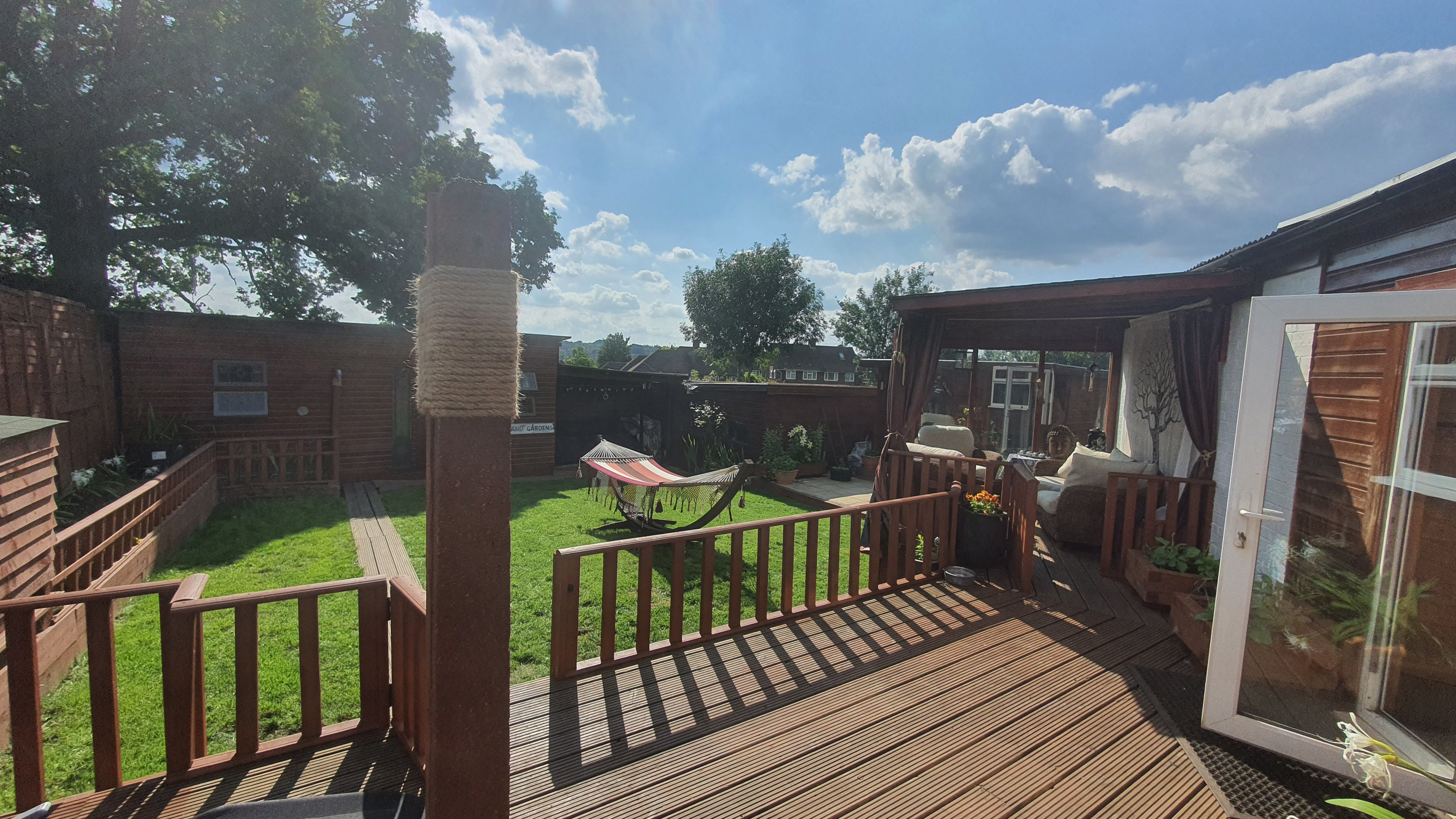 Image of a garden with the decking complete and the view of an outdoor sitting area with cushions.