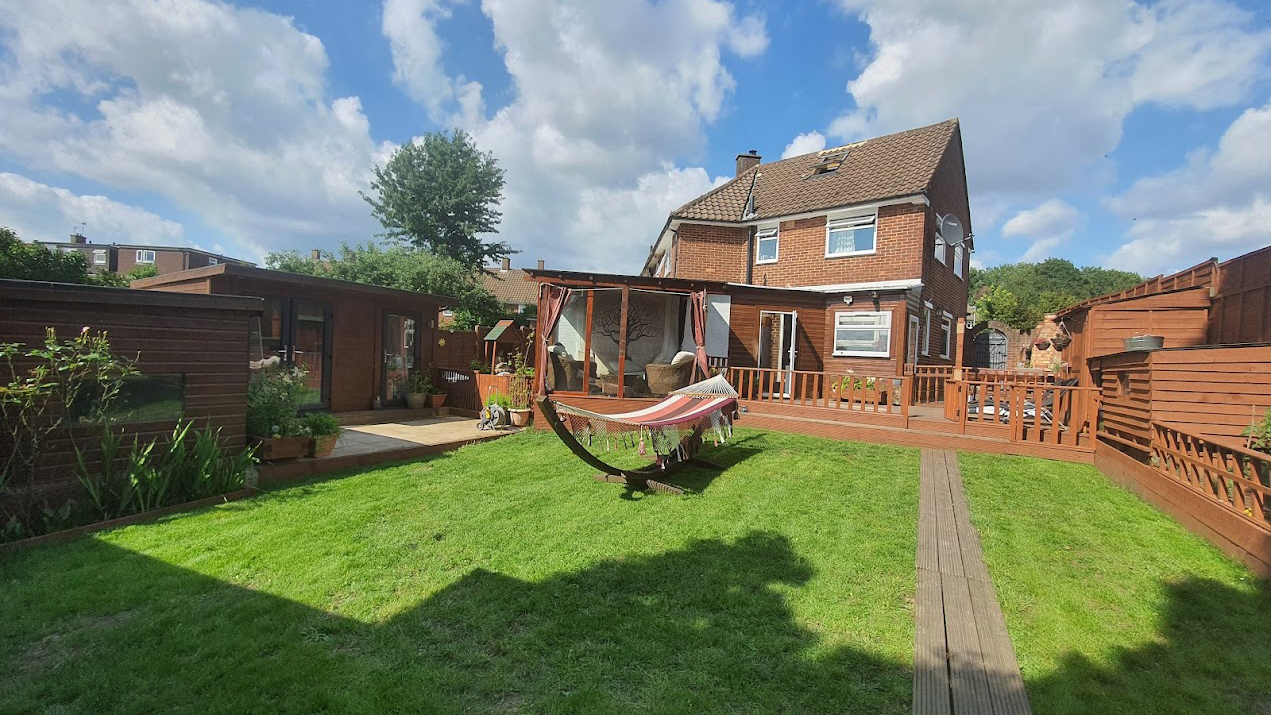 Clean lawn cut around a patio with a hammock in the middle of the garden.