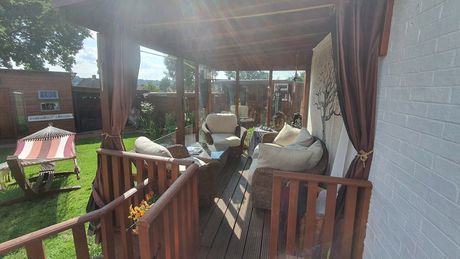 Outdoor seating area on the decking, with a wooden roof.