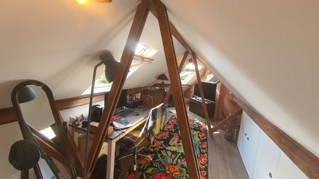 Beams holding the ceiling, and a desk within the attic.