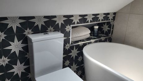 Bathroom with toilet and bath placed on the floor. The wall has a white star with a black background design.